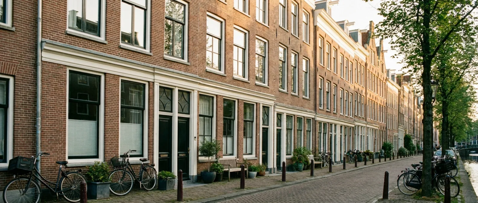 Breed beeld van een gerenoveerde bakstenen gevel van een Amsterdams herenhuis in avondlicht